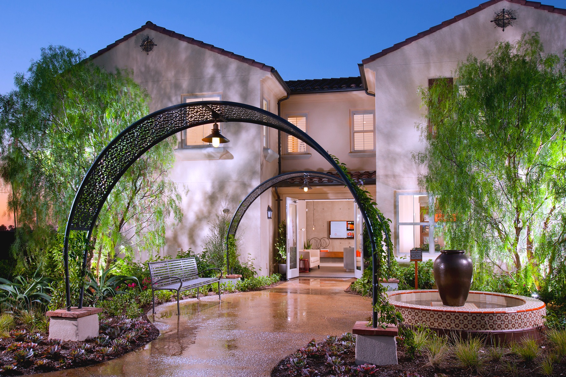 Caserta sales office — courtyard entry with arched trellis at dusk